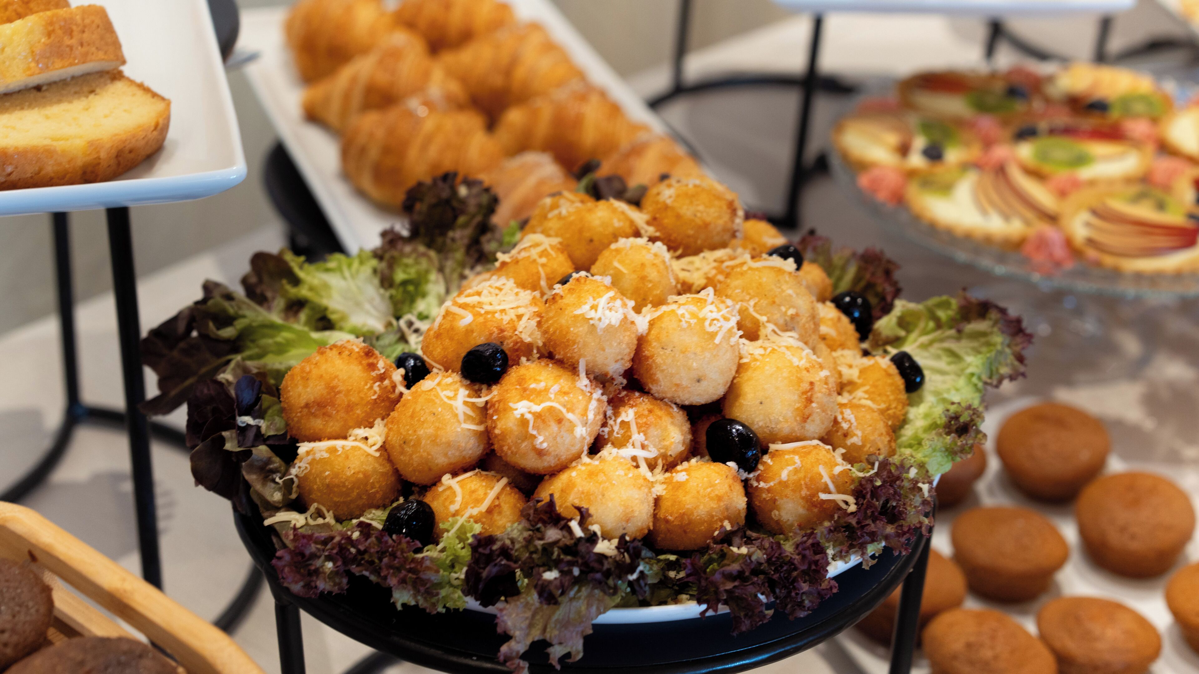 A buffet with various food items including croissants, tater tots, and a salad.