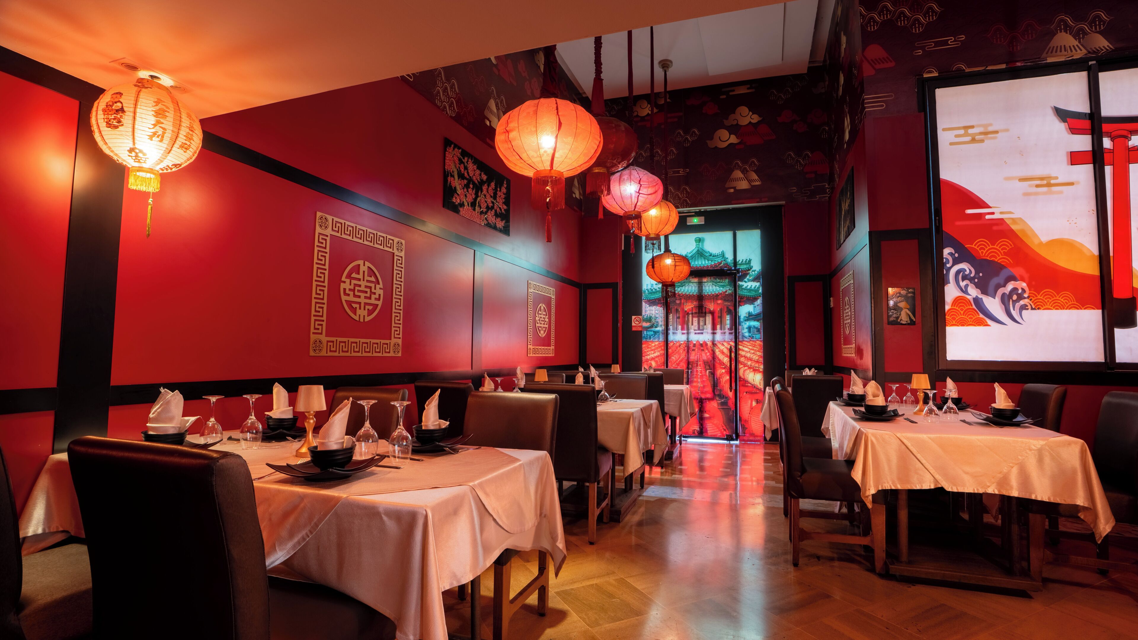 Un restaurante con paredes rojas, faroles chinos tradicionales y mesas dispuestas para comer.
