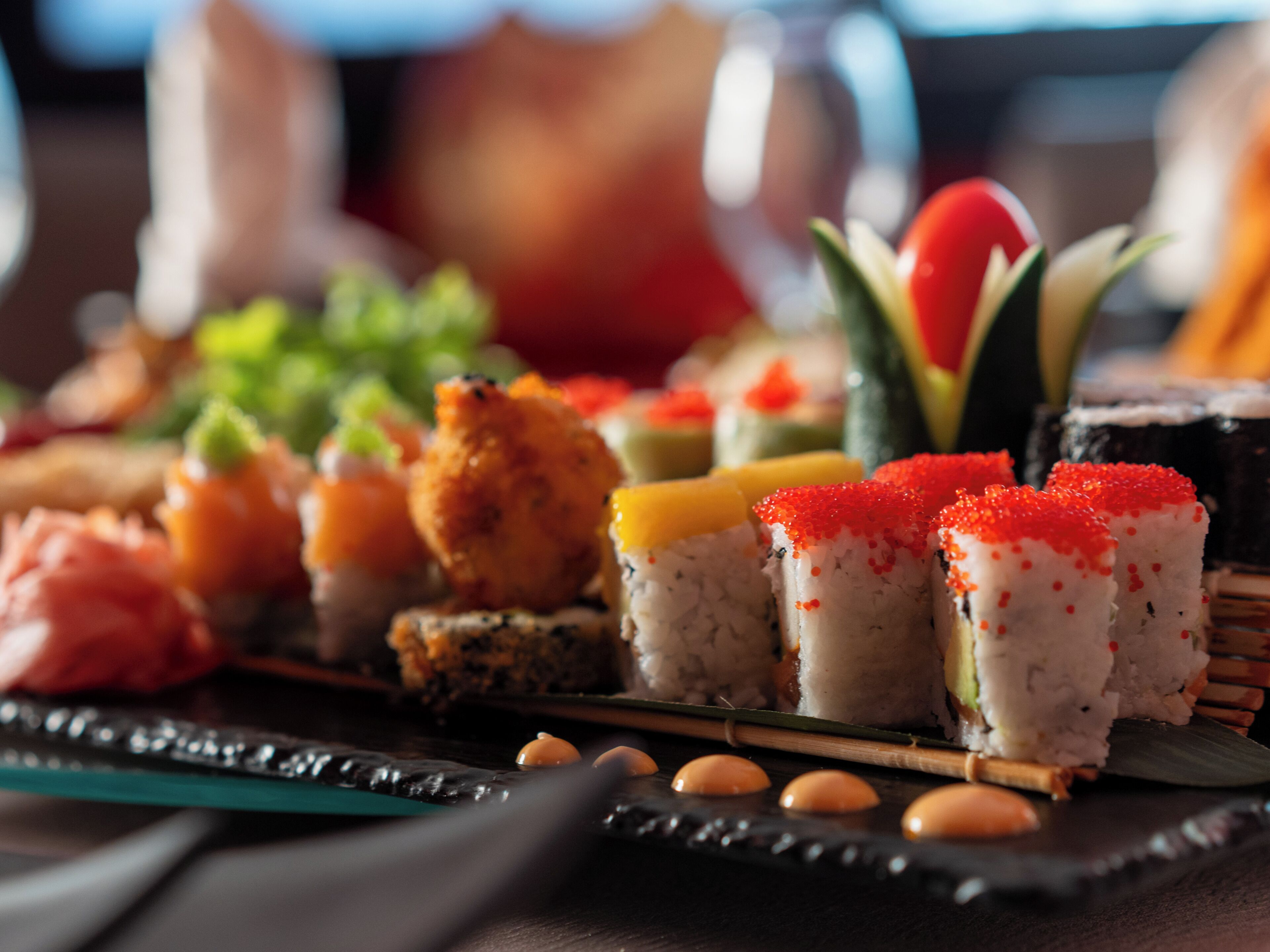 A variety of sushi dishes on a black tray.