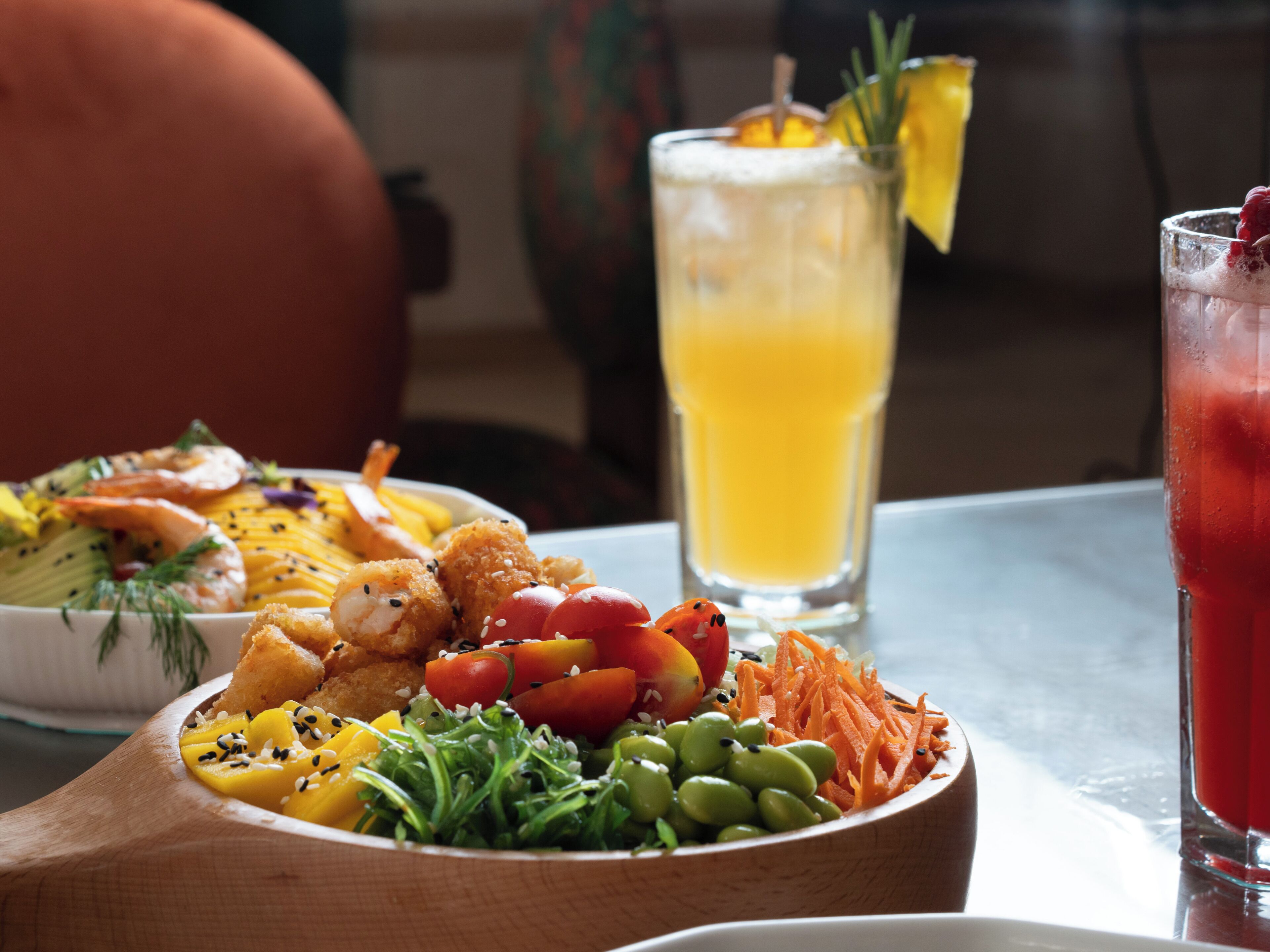 A dining table with a variety of dishes, including a salad, shrimp, and a glass of orange juice.