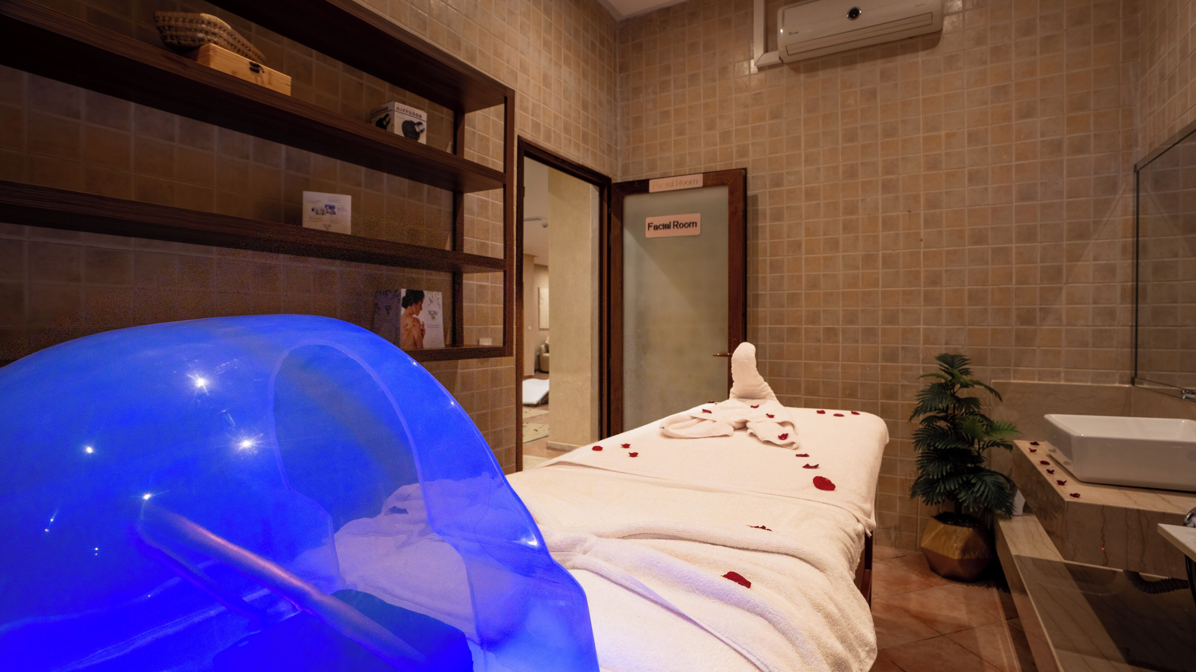 A spa room with a massage table, a sink, and a shower area.