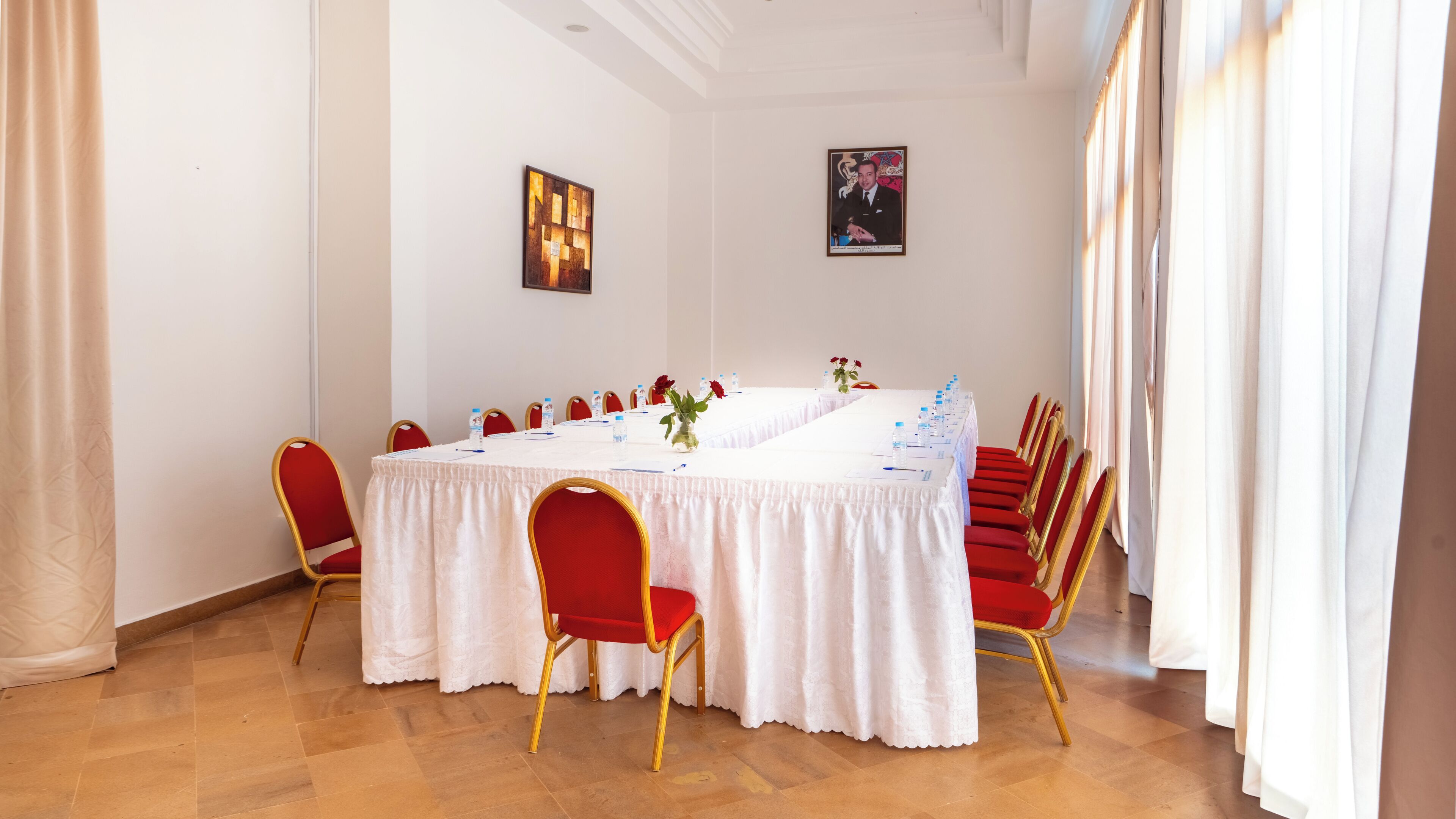 A conference room with a long table, red chairs, and white tablecloths.
