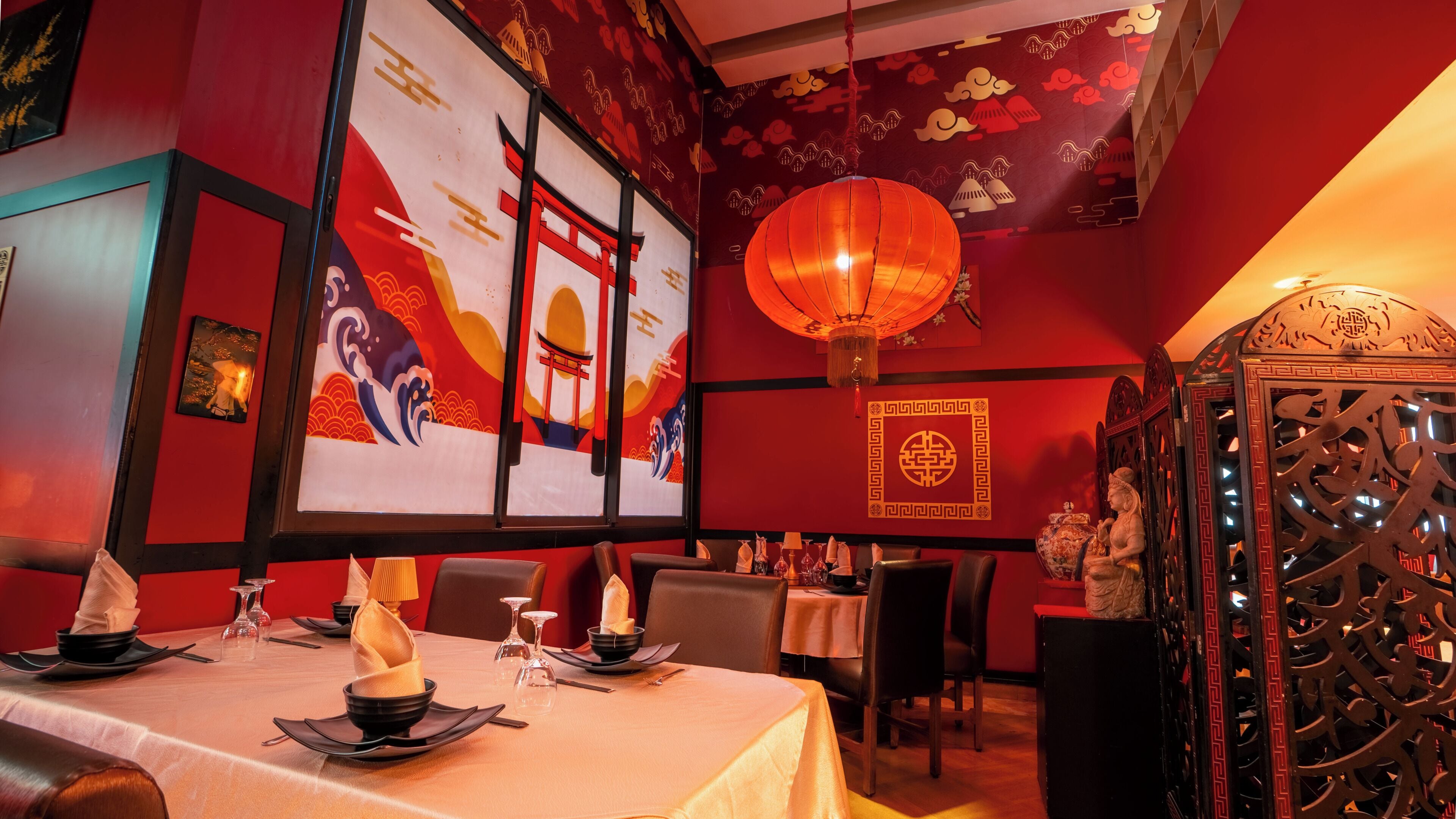 Interior de restaurante con paredes rojas, decoración china tradicional y una mesa lista para comer.