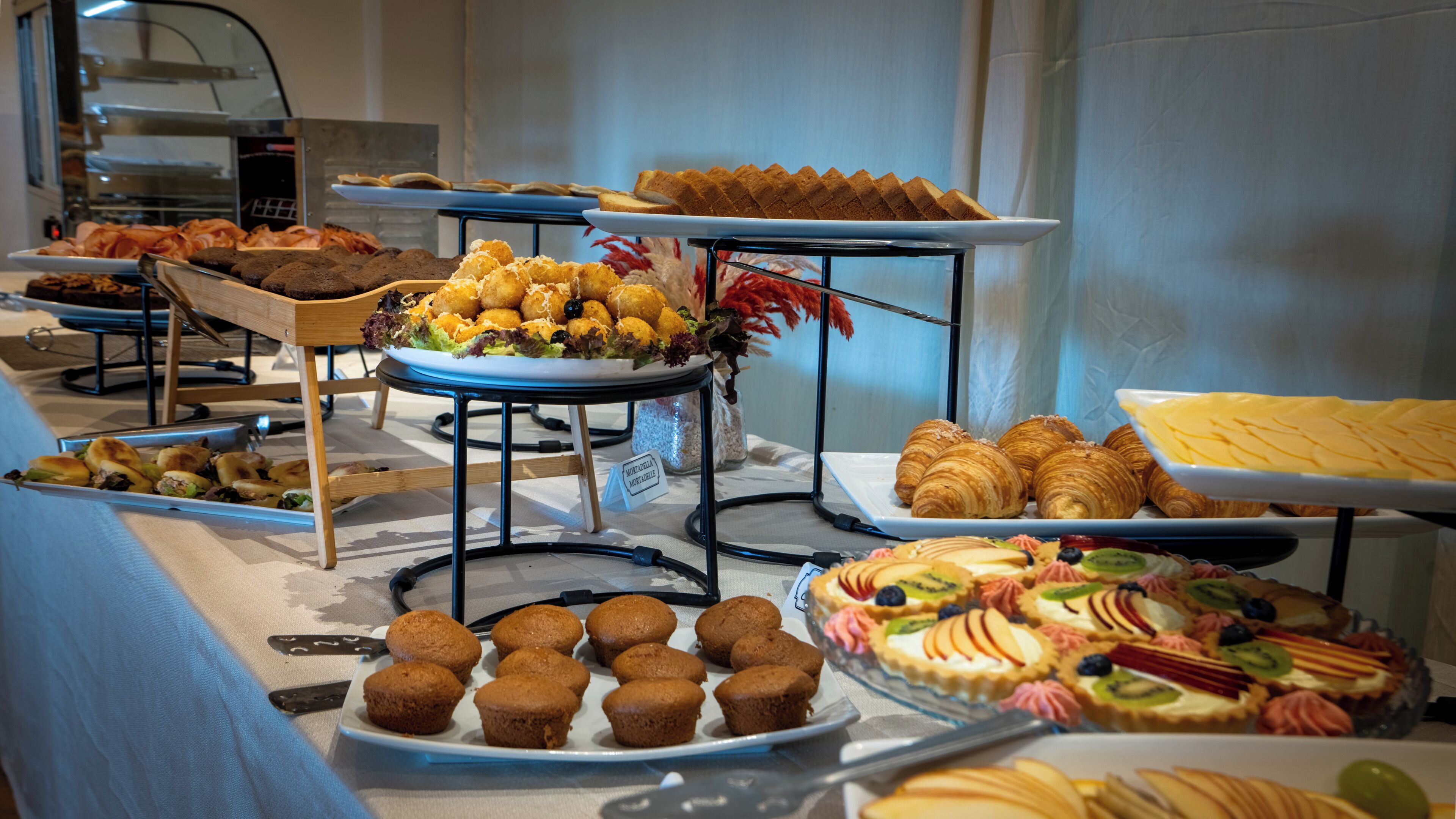 A buffet with various food items including pastries, muffins, and a variety of desserts.