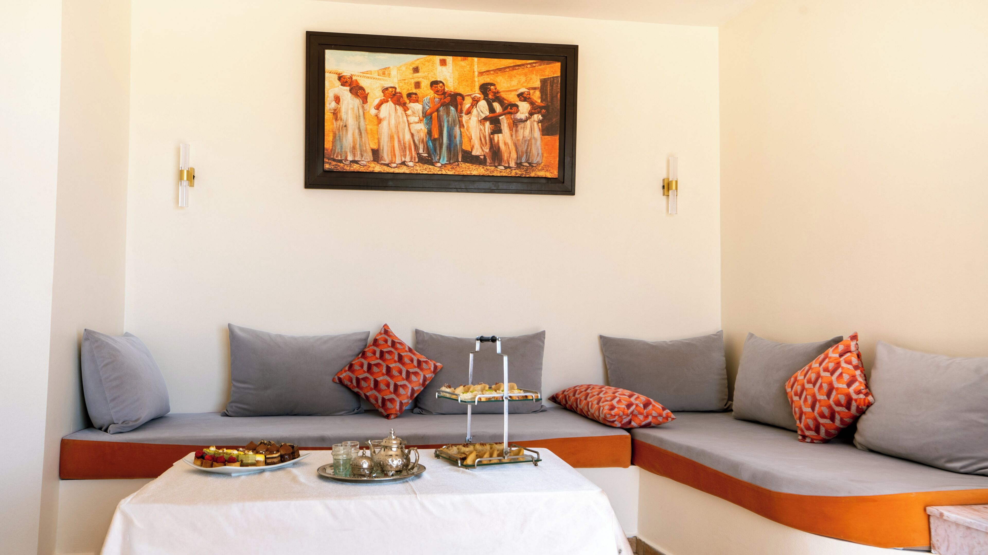 A room with a sofa set, a table with a tray of food, and a framed picture on the wall.