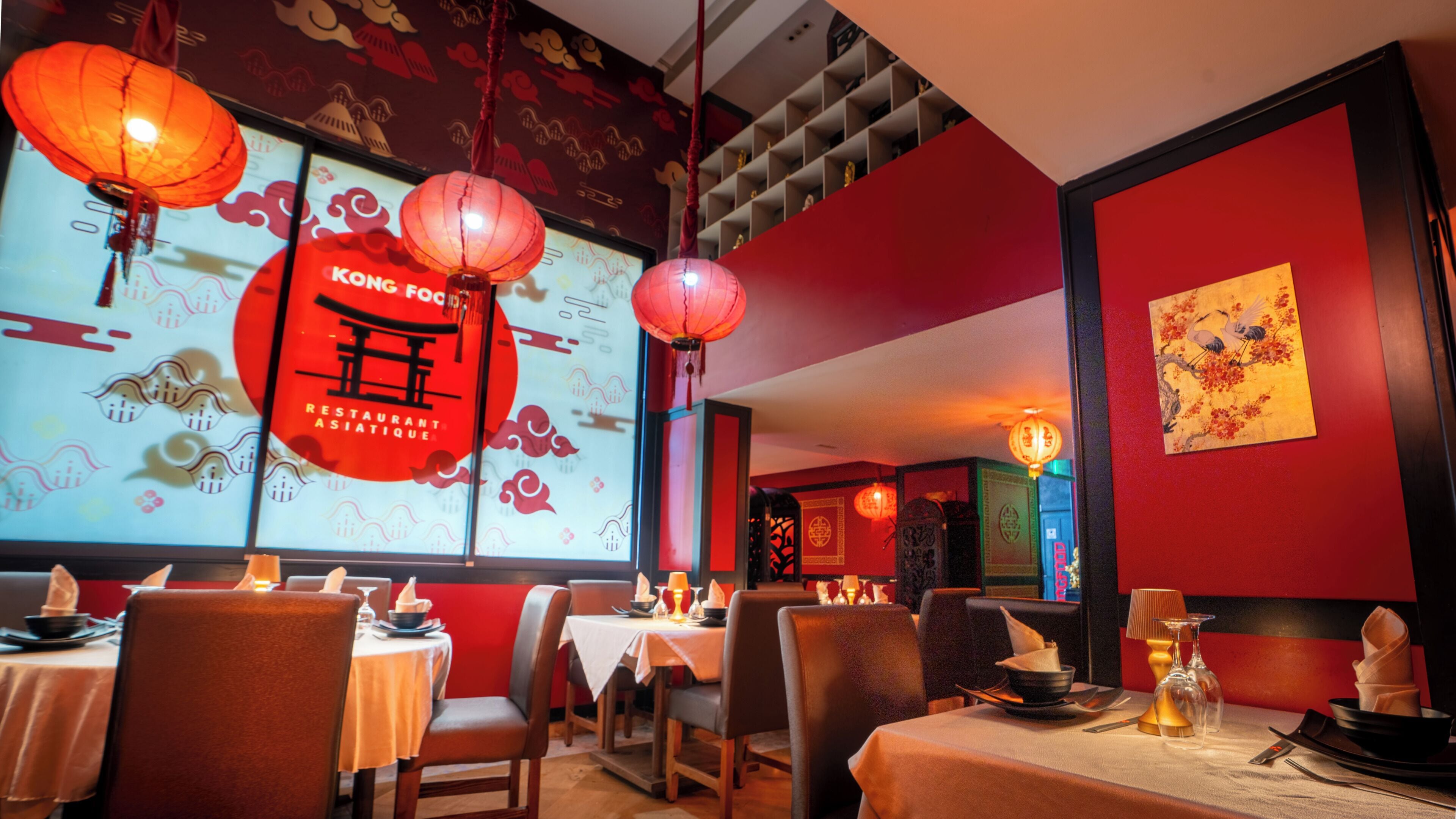 Interior de restaurante con paredes rojas, decoraciones chinas tradicionales y mesas dispuestas para comer.