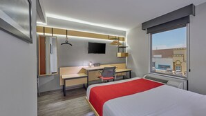 A hotel room with a bed, desk, chair, and a TV on the wall. - City Express by Marriott Mexicali (Mexicali)