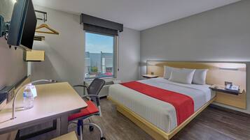 Une chambre d’hôtel avec un lit, un bureau, une chaise et une fenêtre donnant sur un paysage agréable.