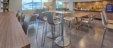 A modern dining area with a long wooden table, multiple chairs, and a bar counter.