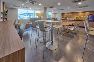 Un comedor moderno con una larga mesa de madera, varias sillas y una barra.