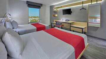 Habitación de hotel con dos camas, un escritorio, una silla, un televisor y un ventanal grande.