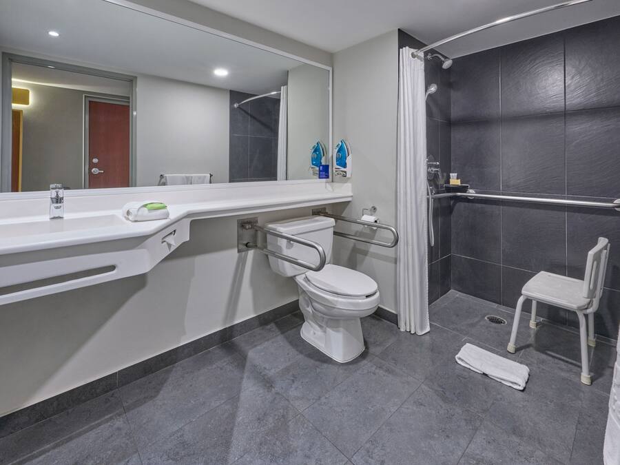 Un baño moderno con un lavabo, inodoro y ducha blancos.