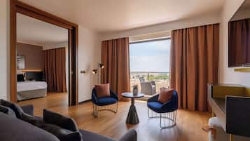 A hotel room with a bed, two armchairs, a small table, and a TV.