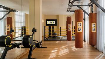 A gym with punching bags, exercise equipment, and a mirrored wall.
