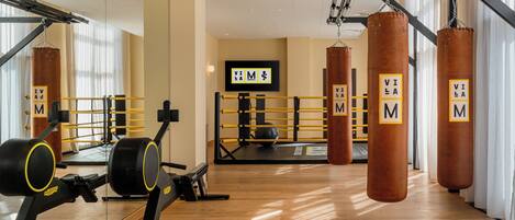 A gym with punching bags, exercise equipment, and a mirrored wall.