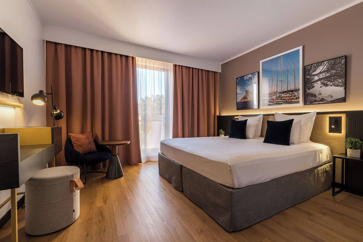 Una camera d'albergo moderna con un letto grande, una scrivania, una sedia e un tavolino.