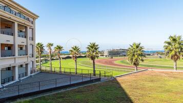 A hotel with a view of a sports field, palm trees, and a Ferris wheel in the background.