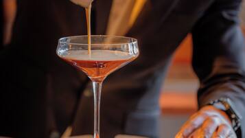 A bartender pouring a drink into a martini glass.