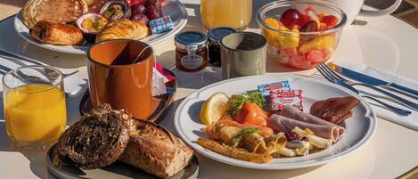 A breakfast table with various dishes, drinks, and condiments.