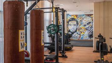 Une salle de sport équipée de matériel de musculation, ornée d’une fresque murale et dotée d’un plancher en bois.