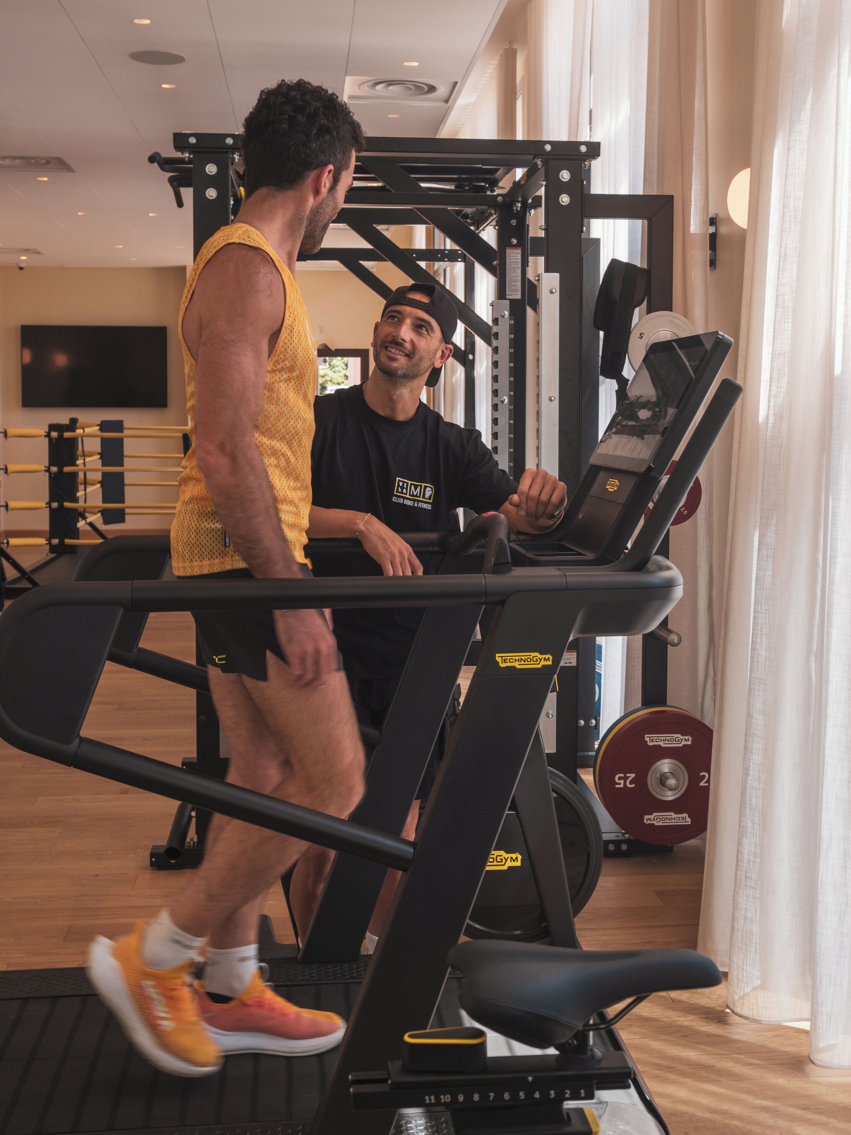 Un gimnasio con cintas de correr, máquinas de pesas y una pantalla de televisión.