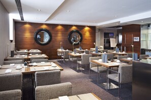 A modern hotel lobby with multiple seating areas, wooden panel walls, and large mirrors. - AC Hotel Recoletos by Marriott (Madrid)