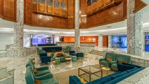 Un vestíbulo amplio con columnas de mármol, un mostrador de recepción y una zona de estar con sofás y sillones.