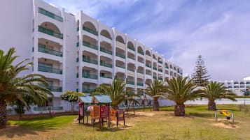 A multi-story hotel with a white facade and green balconies.