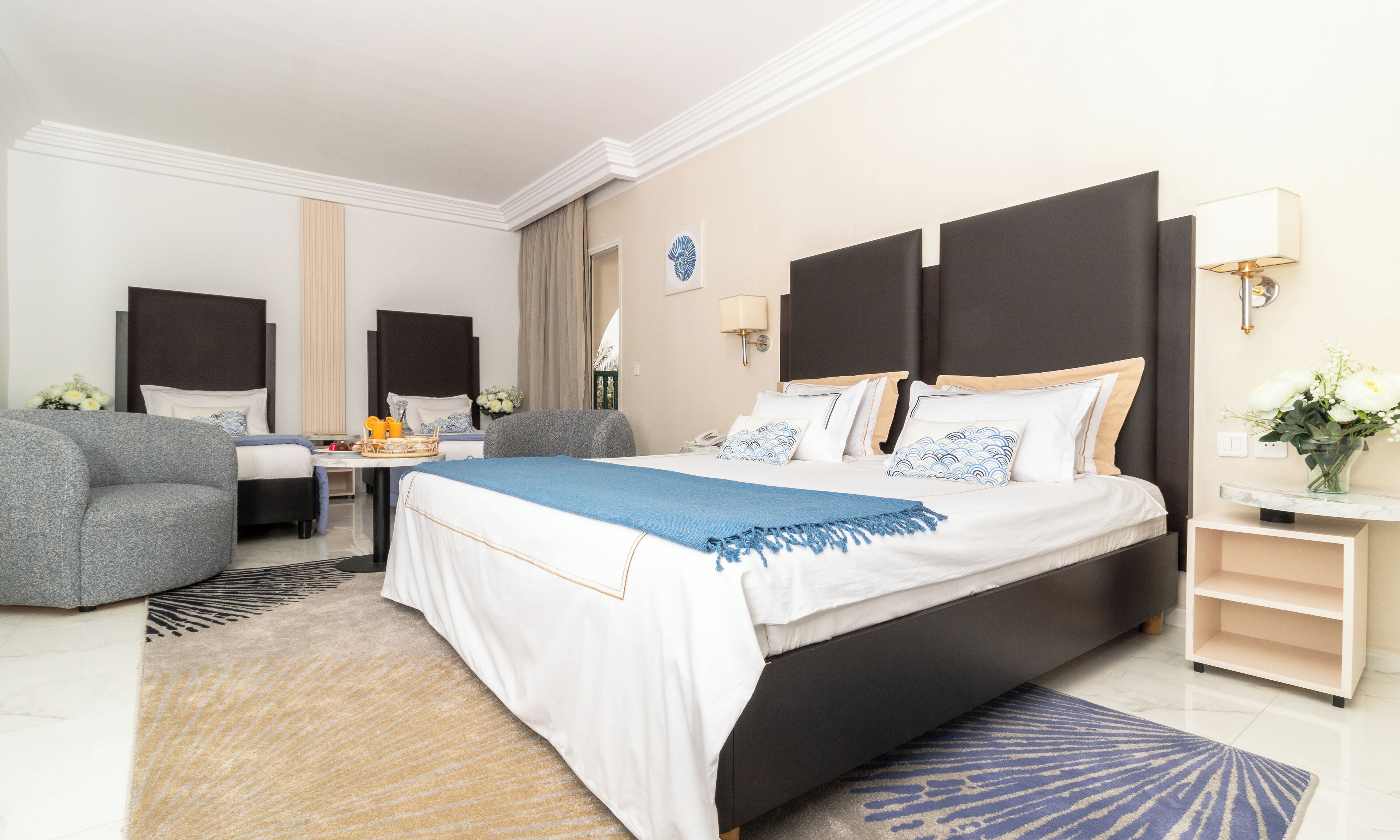 A hotel room with a large bed, a desk, a chair, and a sofa.