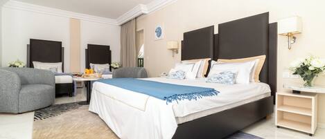 A hotel room with a large bed, a desk, a chair, and a sofa.