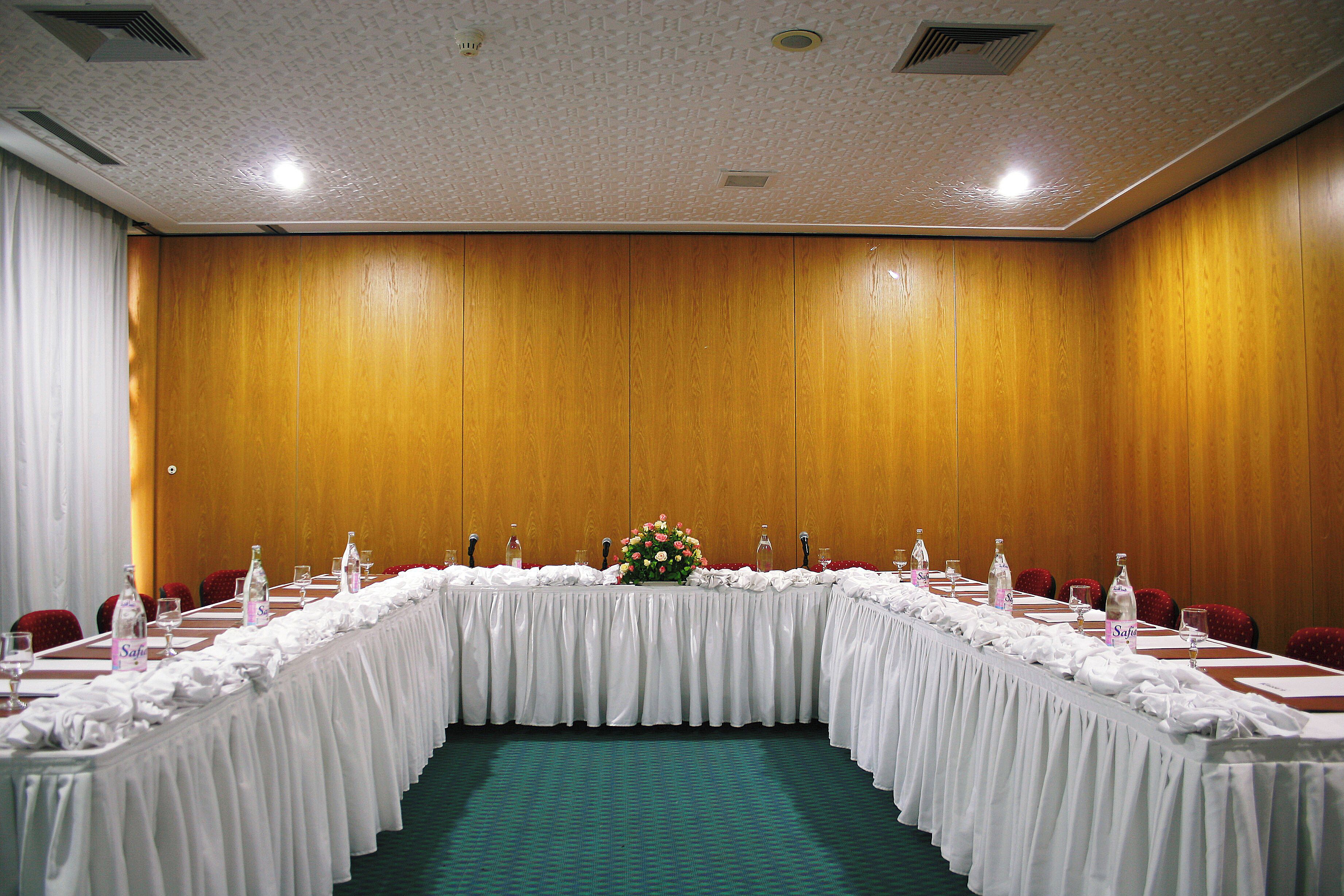A conference room with a long table, chairs, and a floral centerpiece.