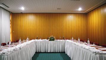 Un salón de conferencias con una larga mesa, sillas y un centro de mesa floral.