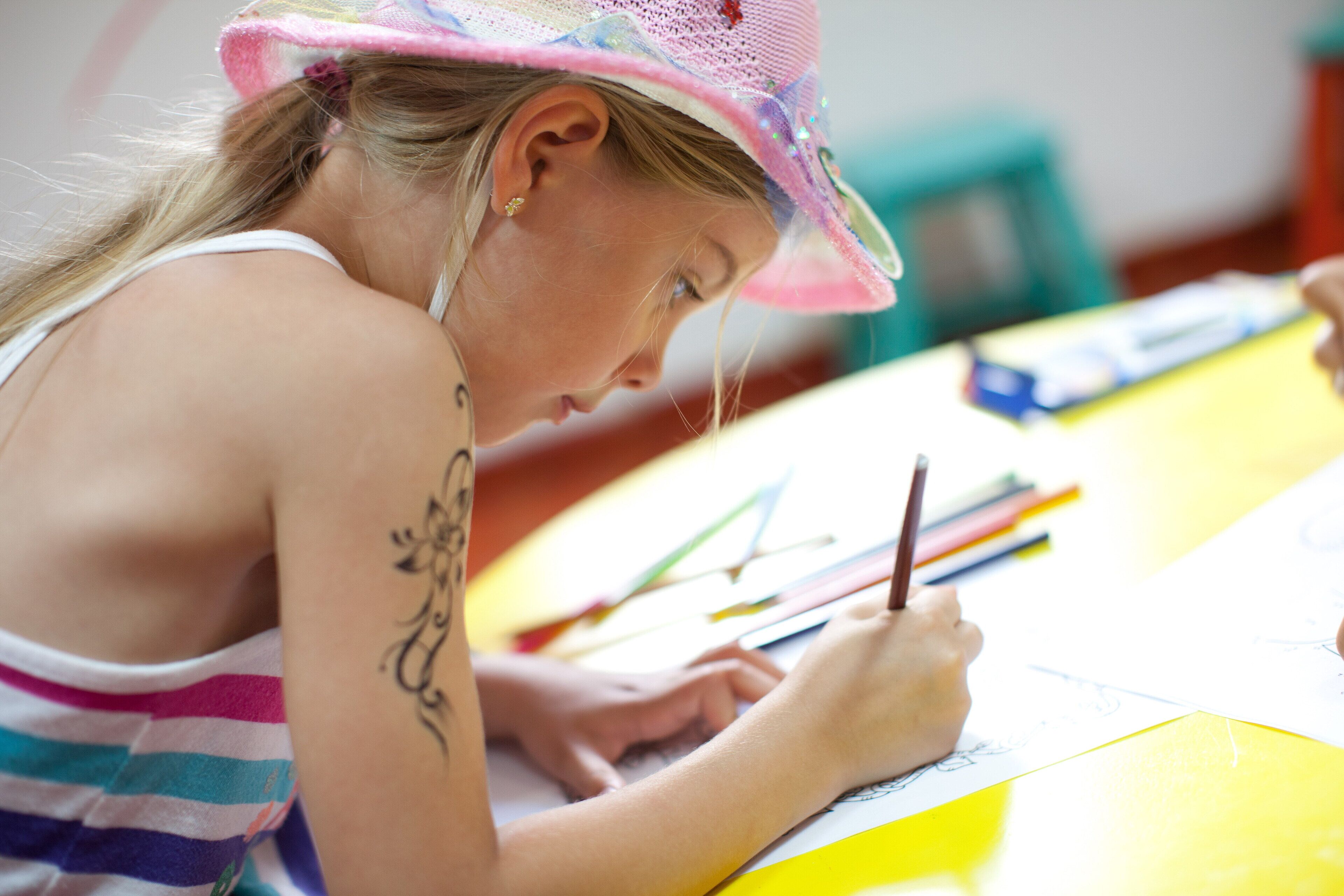 Une personne est assise à une table et dessine avec des crayons de couleur et un carnet de croquis.