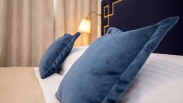 A bed with blue pillows and a white mattress, a lamp on a bedside table, and a dark headboard with a geometric design.