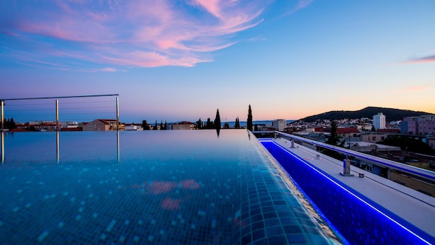 An infinity pool with a view of a cityscape and a hill in the distance. - Art Hotel (Split)
