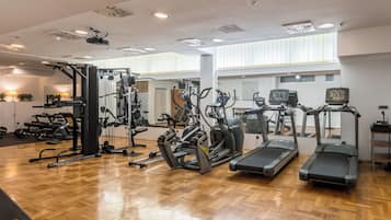 A gym with exercise equipment, a wooden floor, and large windows.