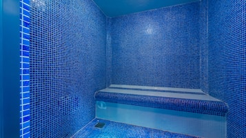 Enclosed bathroom with a bench and sink area.
