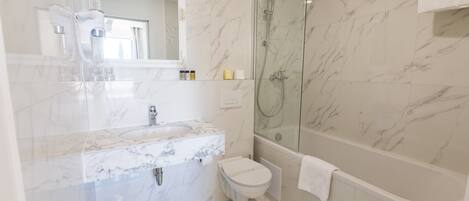 A bathroom with a marble sink, toilet, and a glass-enclosed shower.