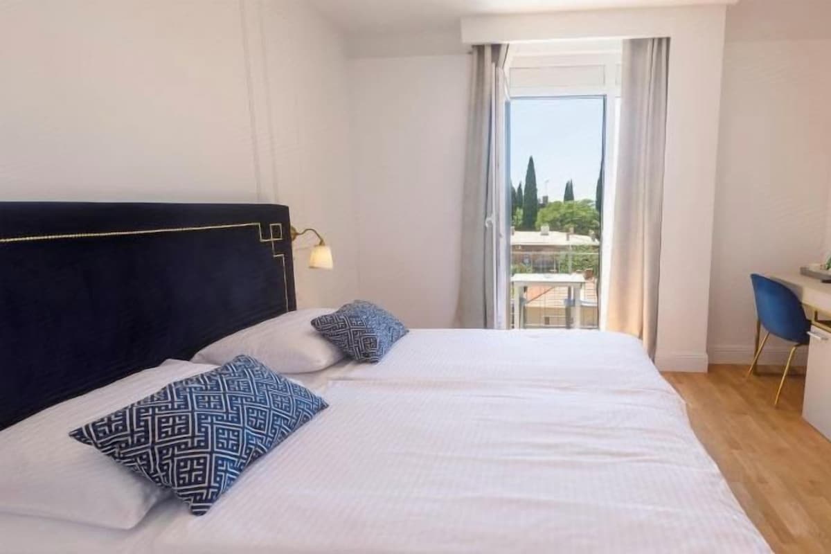 Quarto de hotel com cama, escrivaninha e vista para o exterior.