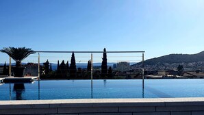 A rooftop infinity pool with a clear view of the city and mountains in the background.