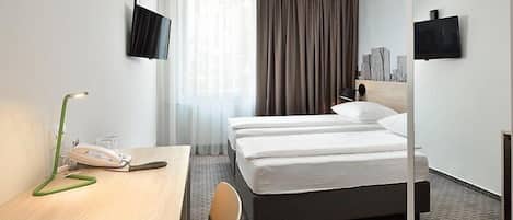 Habitación de hotel con dos camas, un escritorio con teléfono y dos televisores instalados en la pared.