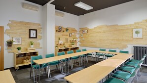Une salle de conférence avec une longue table, des chaises vertes, des panneaux muraux en bois et des unités de climatisation.