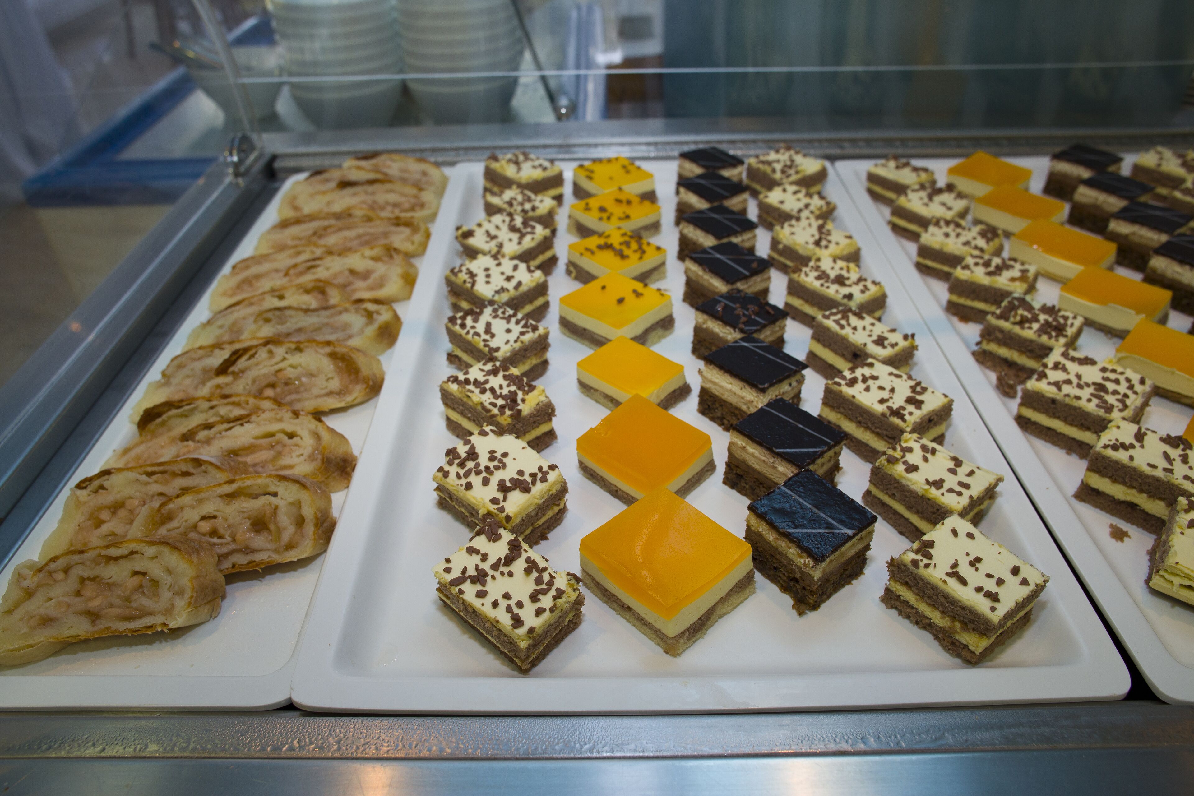 Una vitrina mostra diferents postres, com a pastissos i forns, disposats en files.