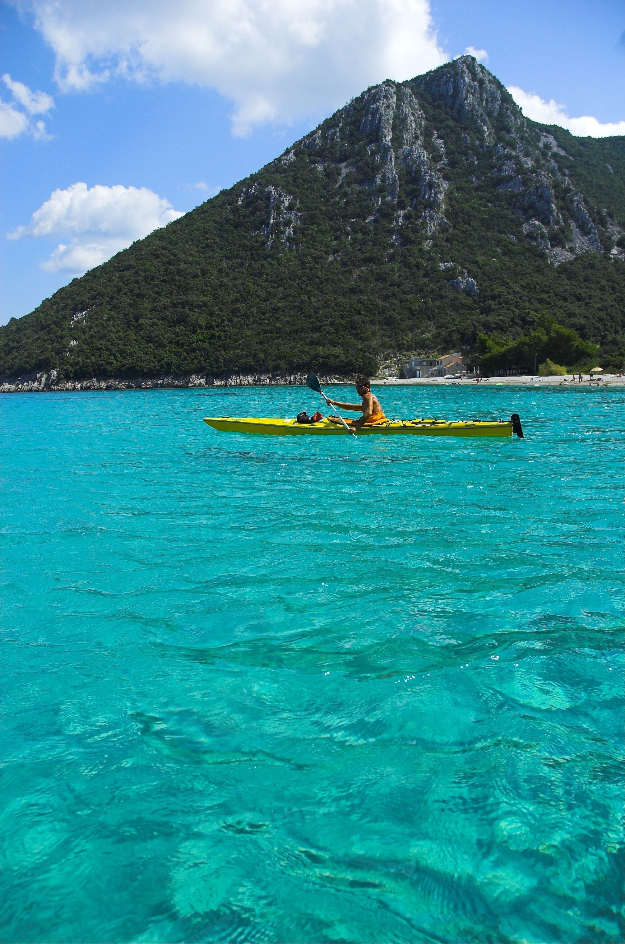 Un kayak sobre aguas turquesas con una montaña al fondo.
