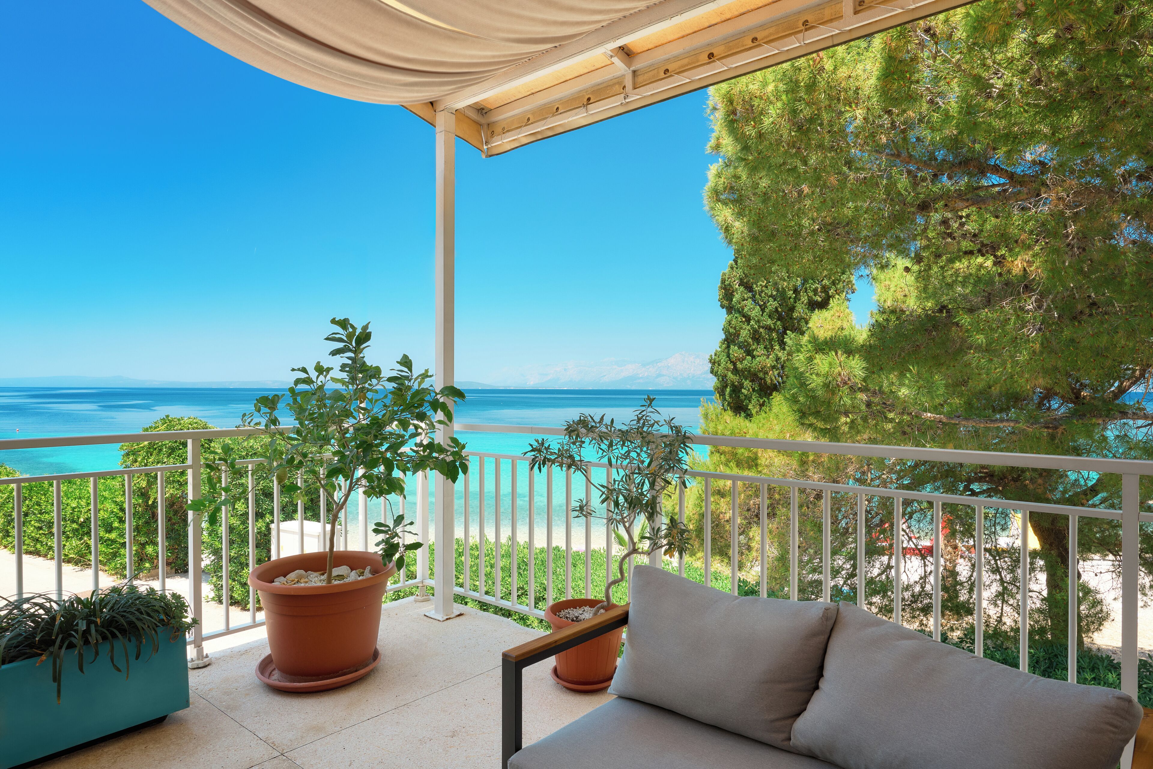 Ein Balkon mit Meerblick, Blumentöpfen und einer Couch.