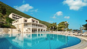 Una piscina con sillas de descanso y un edificio con balcones.