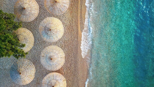 Vista aérea de una playa con varios sombrillas de sol alineadas en filas.