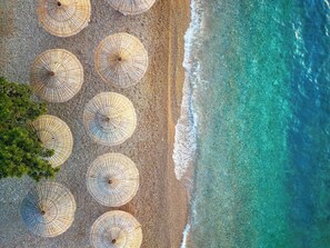 Vista aérea de una playa con varios sombrillas de sol alineadas en filas.