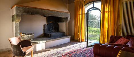 A cozy living room with a fireplace, a red sofa, and a patterned rug.