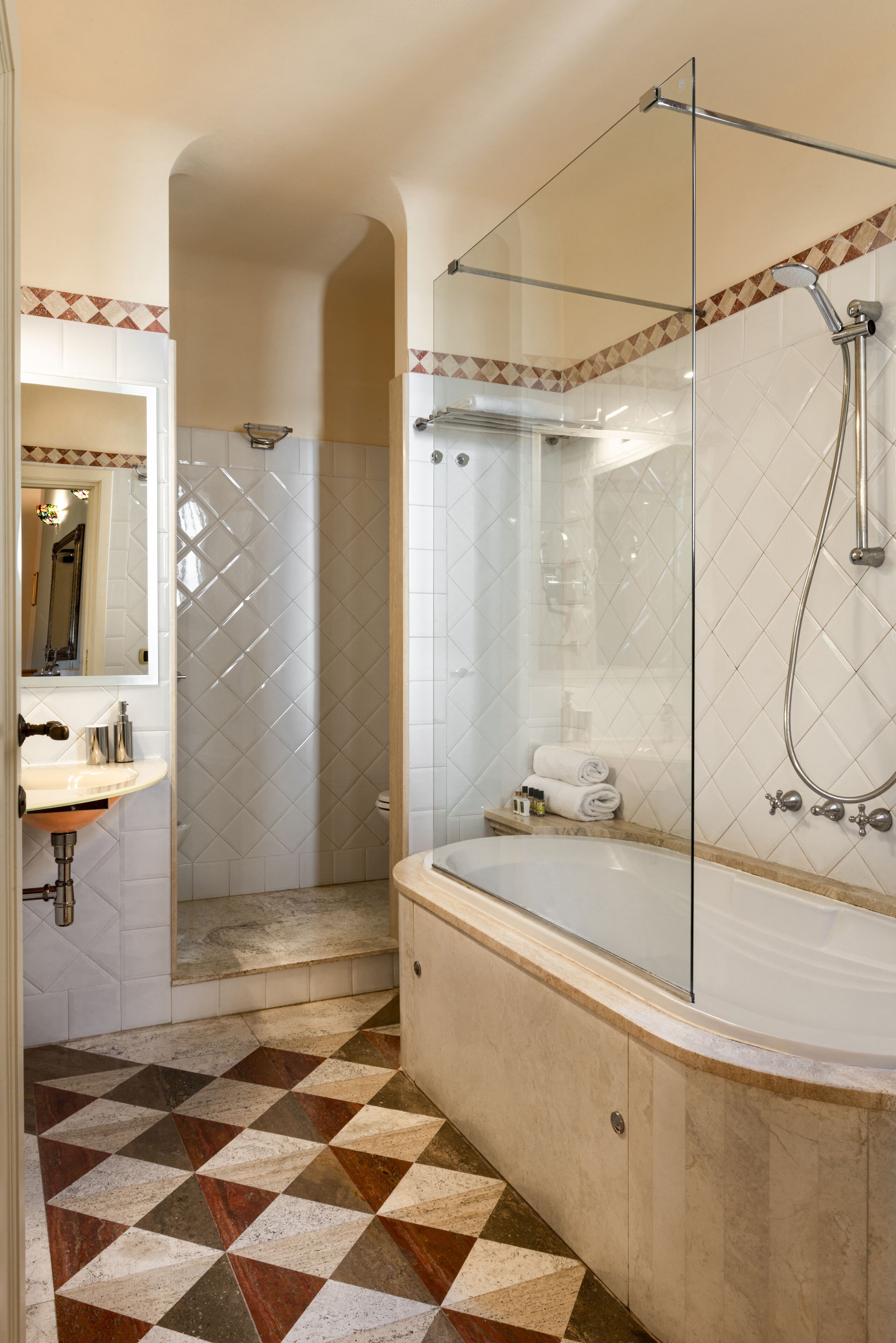 Ein Badezimmer mit einer gläsernen Duschkabine, einer freistehenden Badewanne und einem Waschbecken mit Spiegel.